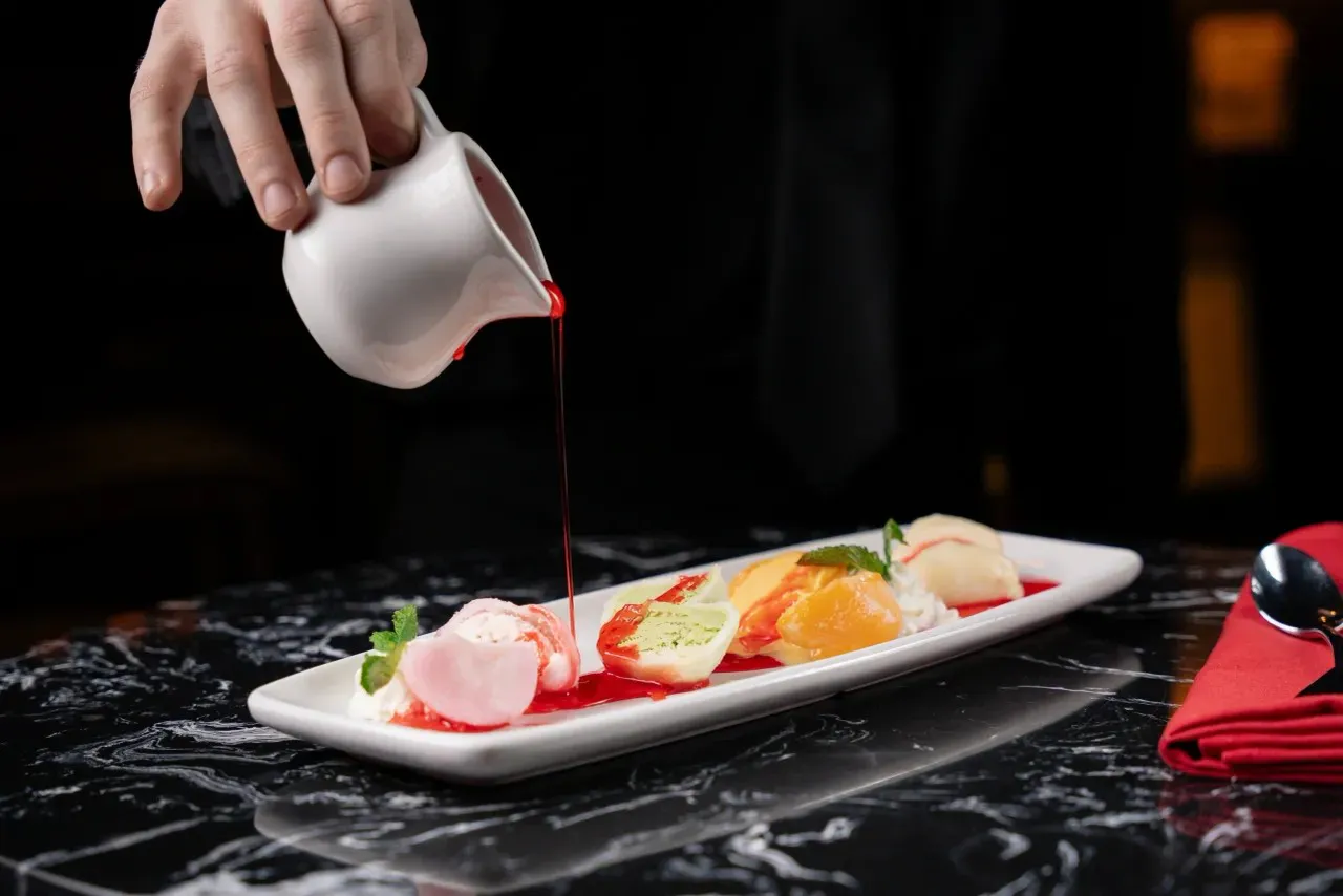 Assorted fruit dessert being drizzled with berry sauce at Shun Lee, a Chinese Restaurant in Lexington