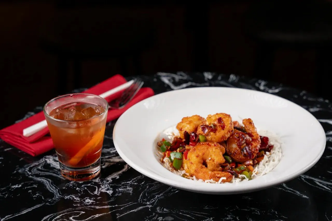 Spicy shrimp over rice paired with iced cocktail at Shun Lee, a Chinese Restaurant in Lexington